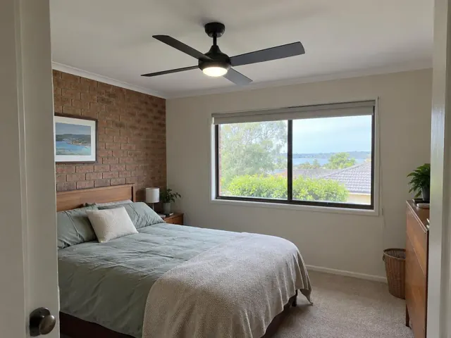 Bedroom with a ceiling fan on a white ceiling above a bed and window in Eleebana