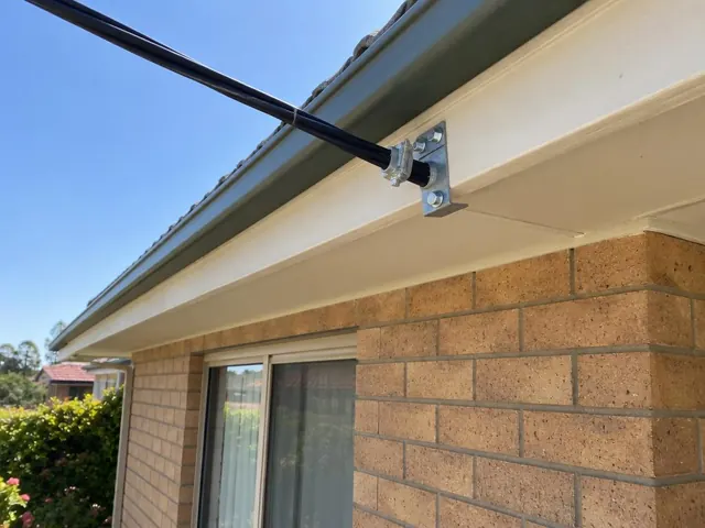 Overhead service cable fixed to a bracket on a brick house eave in Valentine