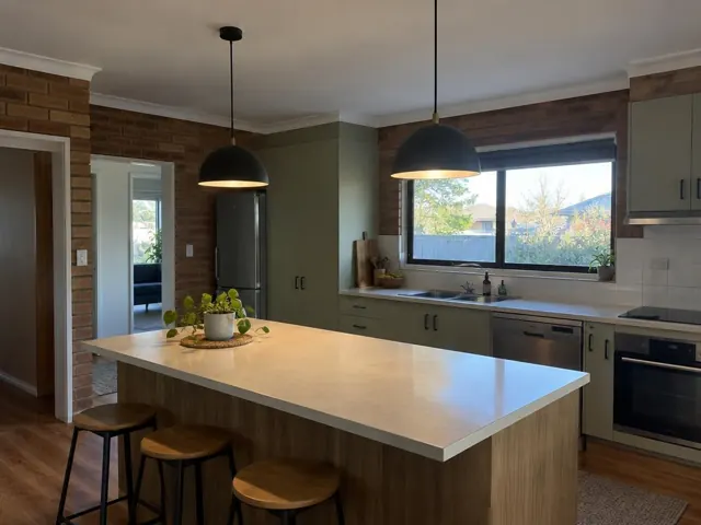 Two black pendant lights above a kitchen island in a brick and timber kitchen in Warners Bay